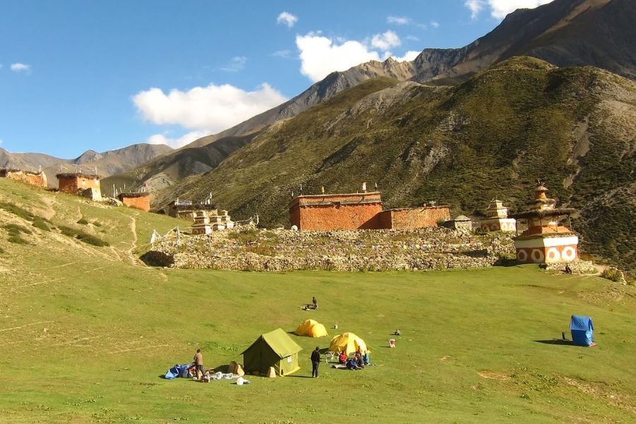 Colorful tents camping near traditional Tibetan stone buildings in Upper Dolpo valley
